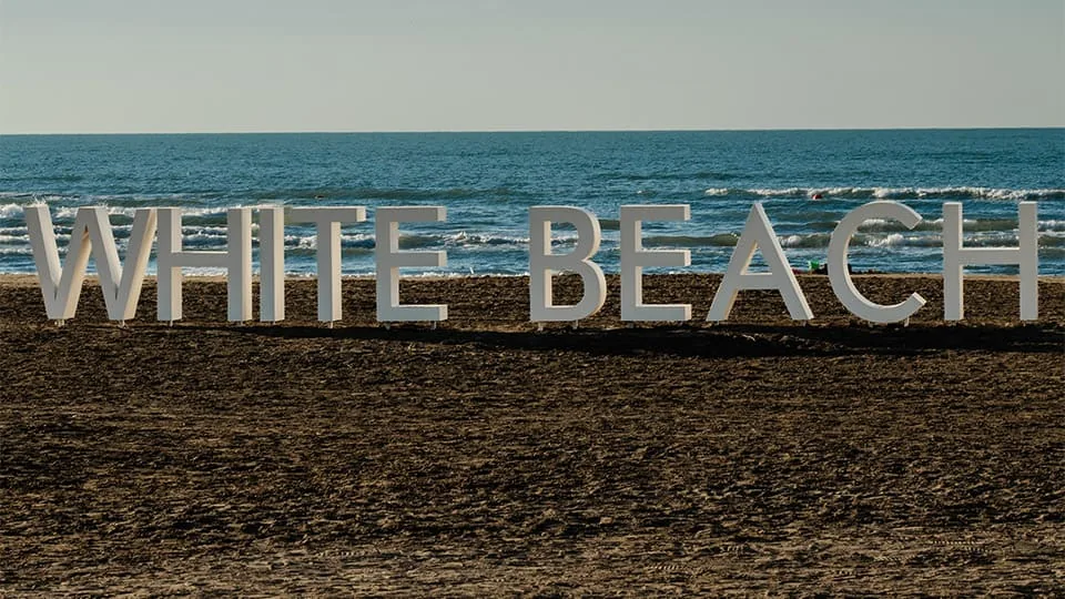 האותיות WHITE BEACH על חול החוף